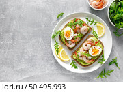 Toast with shrimps, avocado guacomole, arugula and boiled egg, top view. Стоковое фото, агентство Ingram Publishing / Фотобанк Лори