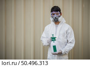 Portrait Disinfection specialist man in PPE suit, gloves, mask and face shield performing public decontamination, standing and holding bottle for spray disinfectant to remove covid-19  . Стоковое фото, агентство Ingram Publishing / Фотобанк Лори