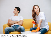 Asian young couple quarrels while cleaning in the living room, Young woman wearing gloves and holding spray bottle in hand with feel dissatisfied her husband, family issues and relationship concept. Стоковое фото, агентство Ingram Publishing / Фотобанк Лори