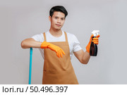 Portrait Happy handsome man in apron and rubber gloves, standing pose with a spray bottle preparing to cleaning, smile and looking to camera, copy space. Стоковое фото, агентство Ingram Publishing / Фотобанк Лори