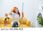 Young housekeeper woman sitting on sofa in living room with feel tired, She wipe sweat and take a break after finishing cleaning the house, copy space. Стоковое фото, агентство Ingram Publishing / Фотобанк Лори