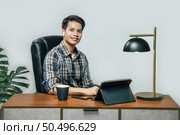Happily Young handsome man with new normal, Stay at home and works from home on digital tablet and use smartphone during self-isolation and quarantine covid-19 coronavirus outbreak. Стоковое фото, агентство Ingram Publishing / Фотобанк Лори