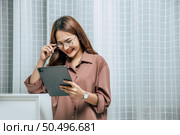 Young woman wearing glasses using technology of digital pen on tablet to working from home during self-isolation and quarantine covid-19 coronavirus outbreak. Стоковое фото, агентство Ingram Publishing / Фотобанк Лори