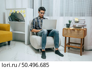 Young handsome man wearing eyeglasses with new normal, Stay at home and works from home on laptop computer while self-isolation and quarantine covid-19 coronavirus outbreak. Стоковое фото, агентство Ingram Publishing / Фотобанк Лори