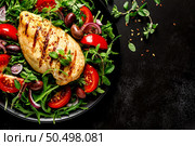 Chicken breast fillet grilled and fresh vegetable green salad with arugula, tomatoes and olives on black background, healthy food, mediterranean diet, top view. Стоковое фото, агентство Ingram Publishing / Фотобанк Лори