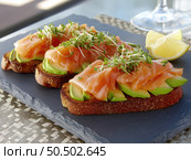 Delicious open-faced sandwiches topped with smoked salmon and avocado. Стоковое AI-изображение, AI-художник Татьяна  Бральнина / Фотобанк Лори