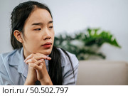 Depressed woman sitting on sofa at home, thinking about important things or feels unhappy with problem in personal life, copy space. Стоковое фото, агентство Ingram Publishing / Фотобанк Лори