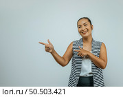 Portrait of Asian woman standing over isolated background with copy space area smiling and looking aside pointing with two hands and fingers to the side. Стоковое фото, агентство Ingram Publishing / Фотобанк Лори