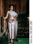 Portrait Asian charming woman wearing beautiful typical Thai dress identity culture of Thailand in ancient temple or famous place with gracefully pose, copy space. Стоковое фото, агентство Ingram Publishing / Фотобанк Лори