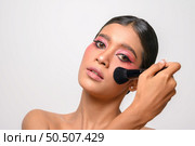woman wearing pink makeup and holding a blush brush. Isolated on white background. Стоковое фото, агентство Ingram Publishing / Фотобанк Лори