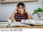 young woman working on a book on the table and having stress. Стоковое фото, агентство Ingram Publishing / Фотобанк Лори