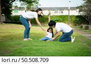 Vacation for a young family Spend this priceless time together playing on the village lawn. A little girl was slightly injured while playing with her parents comforting her at her side. Стоковое фото, агентство Ingram Publishing / Фотобанк Лори