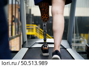 Young female with one prosthetic leg with exercise by walking on a treadmill to practice walking with the other prosthetic leg to be more flexible. Стоковое фото, агентство Ingram Publishing / Фотобанк Лори