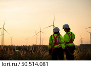 Engineers working on wind farms for renewable energy are responsible for maintaining large wind turbines. Review all tasks of the day while the evening sun shines a beautiful golden light upon both of them. Стоковое фото, агентство Ingram Publishing / Фотобанк Лори