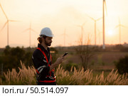 Engineers working on wind farms for renewable energy are responsible for maintaining large wind turbines. Review all tasks of the day while the evening sun shines a beautiful golden light upon both of them. Стоковое фото, агентство Ingram Publishing / Фотобанк Лори