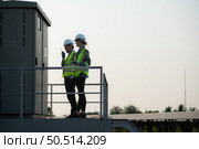 A team of electrical engineers is inspecting an energy storage station of a solar panels in the middle of a hundred acre field of solar panels. Стоковое фото, агентство Ingram Publishing / Фотобанк Лори