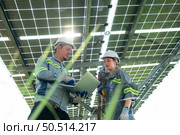A team of electrical engineers is inspecting and maintaining solar panels at a solar panel site in the middle of a hundred acre field. Стоковое фото, агентство Ingram Publishing / Фотобанк Лори