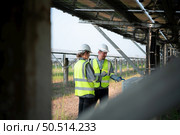 A team of electrical engineers is inspecting and maintaining solar panels at a solar panel site in the middle of a hundred acre field. Стоковое фото, агентство Ingram Publishing / Фотобанк Лори