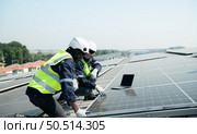 Both of Engineer in charge of solar panel installation The installation of solar energy conversion into electricity for a warehouse is currently being investigated. Стоковое фото, агентство Ingram Publishing / Фотобанк Лори