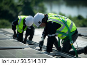 Both of Engineer in charge of solar panel installation The installation of solar energy conversion into electricity for a warehouse is currently being investigated. Стоковое фото, агентство Ingram Publishing / Фотобанк Лори