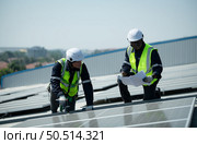 Both of Engineer in charge of solar panel installation The installation of solar energy conversion into electricity for a warehouse is currently being investigated. Стоковое фото, агентство Ingram Publishing / Фотобанк Лори