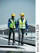 Both of Engineer in charge of solar panel installation The installation of solar energy conversion into electricity for a warehouse is currently being investigated. Стоковое фото, агентство Ingram Publishing / Фотобанк Лори