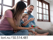 Father and mother with little boy have fun playing with your new toys in the bedroom together. Toys that enhance children’s thinking skills. Стоковое фото, агентство Ingram Publishing / Фотобанк Лори