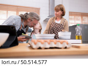 Grandparents with grandchildren and children gather in the kitchen to prepare the day’s dinner. Стоковое фото, агентство Ingram Publishing / Фотобанк Лори