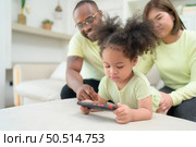 Little children play and learn things in the wide world on tablet. with parents to supervise and help in the living room of the house on vacation. Стоковое фото, агентство Ingram Publishing / Фотобанк Лори