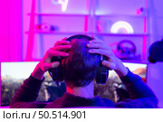 Gamer holding his head with both hands and having a frustrated mood unpleasant when playing a game losing to an opponent. Стоковое фото, агентство Ingram Publishing / Фотобанк Лори