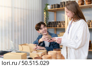A young couple runs a small business making clay jewelry. They support one another as they work toward becoming larger business in the future. Стоковое фото, агентство Ingram Publishing / Фотобанк Лори