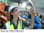 A female engineer installs a program on a robotics arm in a robot warehouse. And test the operation before sending the machine to the customer. Стоковое фото, агентство Ingram Publishing / Фотобанк Лори