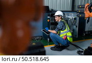 Female Technician Inspecting and repairing robotics arm in robots hangar and test the operation of the machine after being used for a while, as well as updating the software and calibration. Стоковое фото, агентство Ingram Publishing / Фотобанк Лори