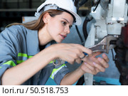 Female Technician Inspecting and repairing robotics arm in robots hangar and test the operation of the machine after being used for a while, as well as updating the software and calibration. Стоковое фото, агентство Ingram Publishing / Фотобанк Лори