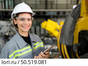 A female engineer installs a program on a robotics arm in a robot warehouse. And test the operation before sending the machine to the customer. Стоковое фото, агентство Ingram Publishing / Фотобанк Лори