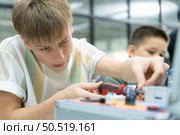 Youngsters utilizing the hand robot technology are having fun learning the electronic circuit board and hand robot controller of robot technology, which is one of the STEM courses. Стоковое фото, агентство Ingram Publishing / Фотобанк Лори