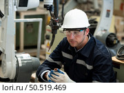 Young male engineers with experience are maintaining and testing the functionality of welding robots. After the hardwork of welding robots. Стоковое фото, агентство Ingram Publishing / Фотобанк Лори