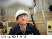 Young male engineers with experience are maintaining and testing the functionality of welding robots. After the hardwork of welding robots. Стоковое фото, агентство Ingram Publishing / Фотобанк Лори