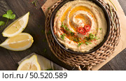 Delicious hummus in ceramic bowl. Colorful snack composition on a black wooden background. Стоковое фото, агентство Ingram Publishing / Фотобанк Лори