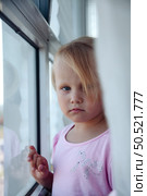 Curious Girl Gazes out the Window, Lost in Thought and Wonder at the World Beyond. Стоковое фото, фотограф Aleksandr Golubev / Фотобанк Лори