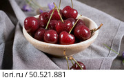 Red fresh cherries in bowls and a bunch of cherries on the table. Стоковое фото, агентство Ingram Publishing / Фотобанк Лори