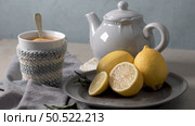 Cup of hot tea with lemon dressed in knitted warm winter scarf on wooden tabletop. Стоковое фото, агентство Ingram Publishing / Фотобанк Лори