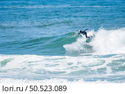 Young athletic surfer rides the wave in Furadouro Beach in Ovar, Portugal. Стоковое фото, агентство Ingram Publishing / Фотобанк Лори