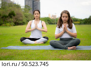 Young female and little girl with outdoor activities in the city park, Yoga is her chosen activity. Стоковое фото, агентство Ingram Publishing / Фотобанк Лори