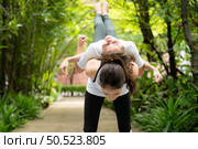 Young female and little girl disciple in the garden there are wooden walkways and a tunnel of fresh green trees. with yoga activities for health. Стоковое фото, агентство Ingram Publishing / Фотобанк Лори