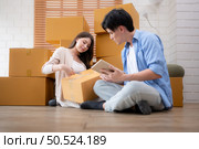 Young asian couple checking boxes being transported into new home with tablet. Стоковое фото, агентство Ingram Publishing / Фотобанк Лори
