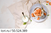 Pancakes with yogurt and tangerines on a light modern kitchen counter top with oat, thyme and mint leaves. Стоковое фото, агентство Ingram Publishing / Фотобанк Лори