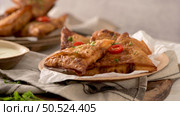 Indian samosas  - fried or baked pastry with savoury filling, popular Indian snacks, served in areca leaf dishes with spices on kitchen countertop. Стоковое фото, агентство Ingram Publishing / Фотобанк Лори