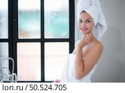 Young woman wrapping in a towel in her hair sitting on the floor in the bathroom at home. Стоковое фото, агентство Ingram Publishing / Фотобанк Лори