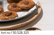 Caramel cookies with pecan nuts served on roud plates, in the kitchen after baking. Стоковое фото, агентство Ingram Publishing / Фотобанк Лори